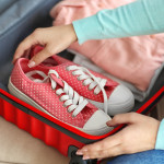 Woman packing her red suitcase, close up