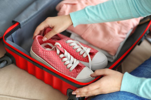 Woman packing her red suitcase, close up