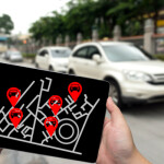 Car sharing service or rental concept. Sharing economy and collaborative consumption. Man hand holding tablet with icons application screen and blur car park background.